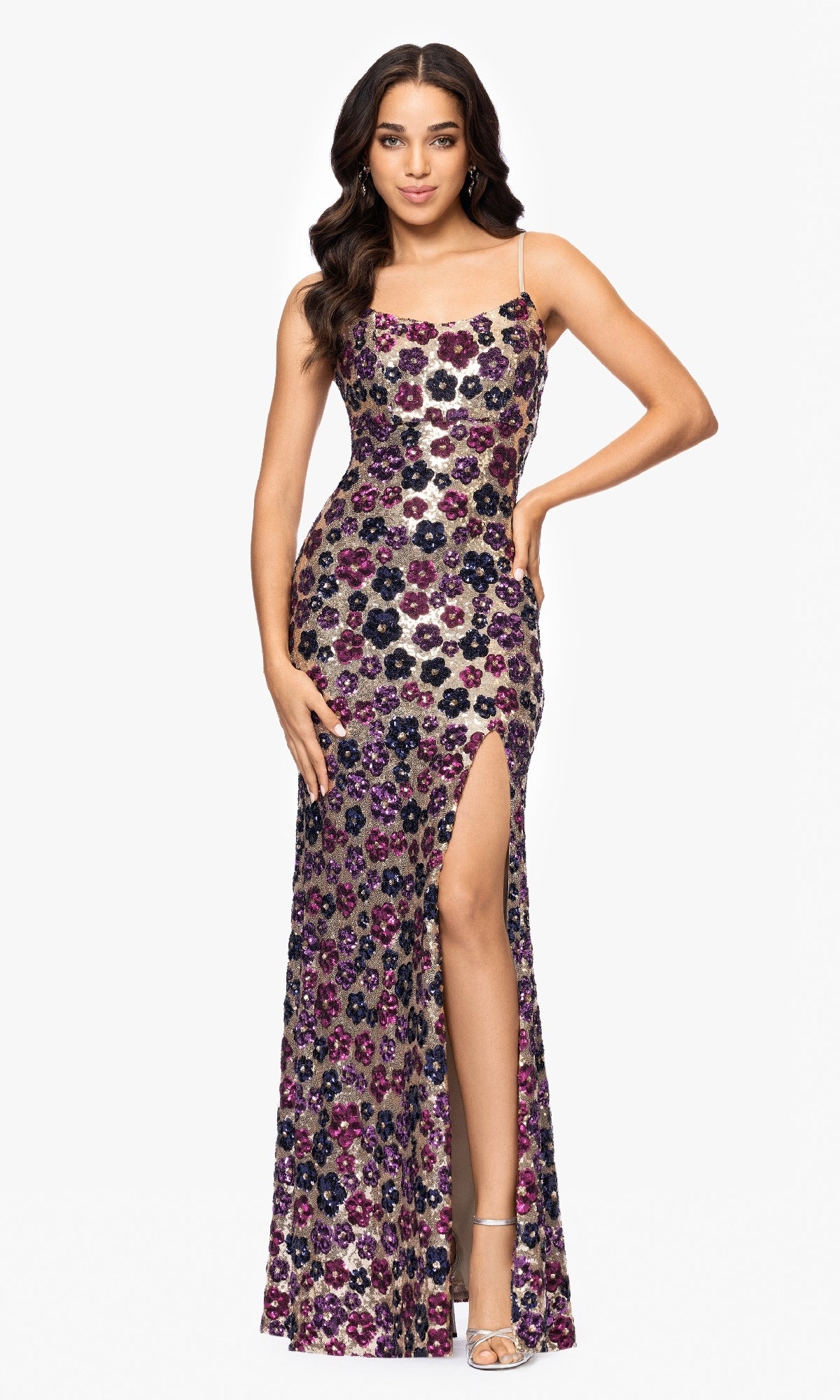 A woman stands facing forward with one hand on her hip, wearing the Betsy & Adam A27017 Floral-Sequin Long Prom Dress featuring a thigh-high slit.